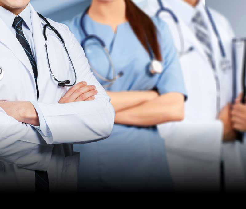 Three doctors, two males and one female, are confidently standing in-line in a brightly lit area.